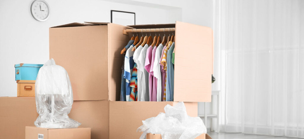 Упаковка одежды из шкафа в специальные гардеробные коробки для перевозки